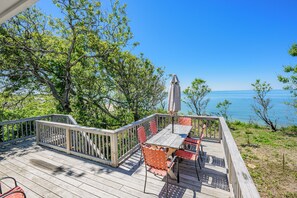 A wooden deck with a table and chairs, a railing, and a view of the water. - Beachfront Home Offering Direct Access to Your Own Private Beach (2386) (Brewster)