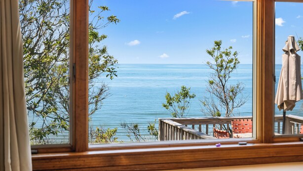 Ein Zimmer mit großem Fenster und Blick auf das Meer sowie einer Holterrasse.
