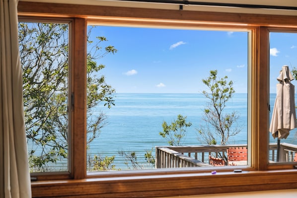 Una habitación con un ventanal grande que ofrece vistas al mar y una terraza de madera.