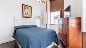Un dormitorio con cama, cómoda, un cuadro y una araña.