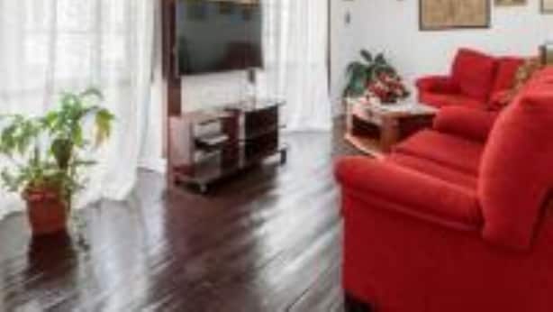 Una sala de estar con un sofá rojo, un televisor y un cuadro en la pared.