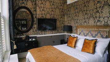 Habitación de hotel con una cama grande, televisión montada en la pared, cómoda y espejo.