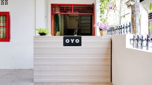 Una recepción con un cartel que dice "OYO" en un edificio moderno con un ventanal de marco rojo y una planta en maceta.