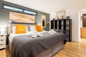 Un dormitorio moderno con una cama grande, una mesita de noche, un armario y obras de arte en las paredes.