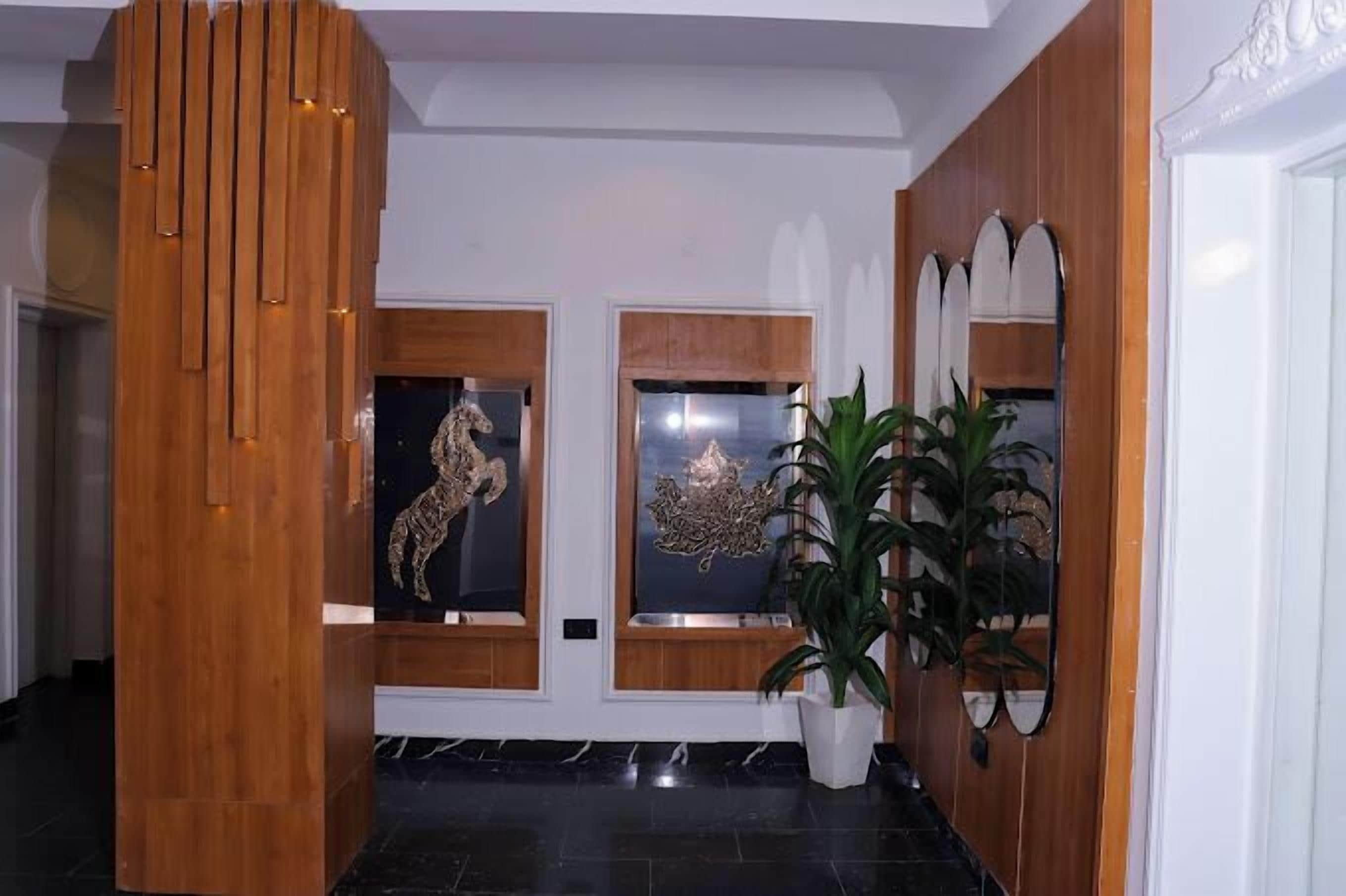 A lobby with a wooden reception desk, two framed artworks, and a potted plant.