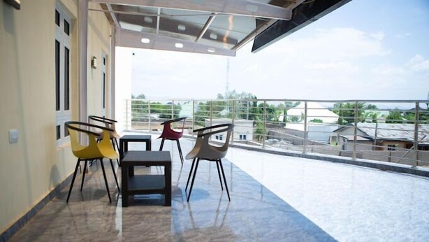 A modern indoor balcony with a clear view of the surrounding area, featuring a seating arrangement with chairs and a table. - Mamma Chare Hotel  (Jimeta)