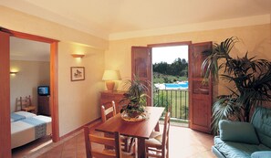 A dining area with a wooden table, chairs, and a lamp. There is a television on a stand, a framed picture on the wall, and a potted plant on the table. - Classical Residence Baia Delle Palme 2 Bedroom Apartment Sleeps 6 Persons T6 (Pula)