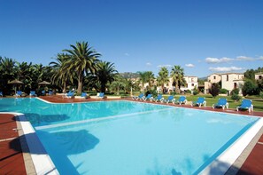 A swimming pool with blue water, surrounded by palm trees and lounge chairs. - Classical Residence Baia Delle Palme 2 Bedroom Apartment Sleeps 6 Persons T6 (Pula)