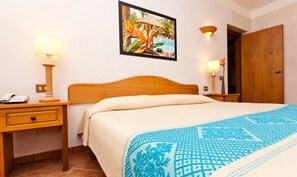 A hotel room with a bed, a nightstand with a lamp, a wooden door, and a framed picture on the wall. - Classical Residence Baia Delle Palme 2 Bedroom Apartment Sleeps 6 Persons T6 (Pula)