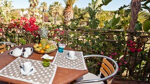 An outdoor dining area with a table set for two, surrounded by lush tropical plants and a palm tree. - Classical Residence Baia Delle Palme 2 Bedroom Apartment Sleeps 6 Persons T6 (Pula)