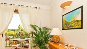 A room with a balcony, a table with chairs, a lamp, a decorative bowl, and a framed picture on the wall. - Classical Residence Baia Delle Palme 2 Bedroom Apartment Sleeps 6 Persons T6 (Pula)