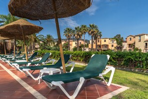 A row of green lounge chairs with white frames on a tiled patio, surrounded by palm trees and a clear blue sky. - Classical Residence Baia Delle Palme 2 Bedroom Apartment Sleeps 6 Persons T6 (Pula)