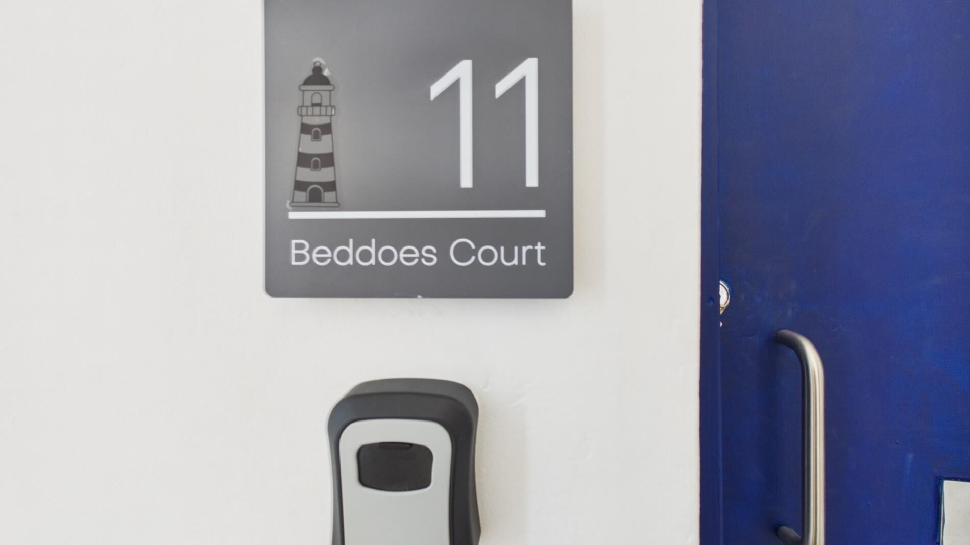 A wall-mounted sign with a lighthouse illustration and the number 11, labeled 'Beddoes Court.'
