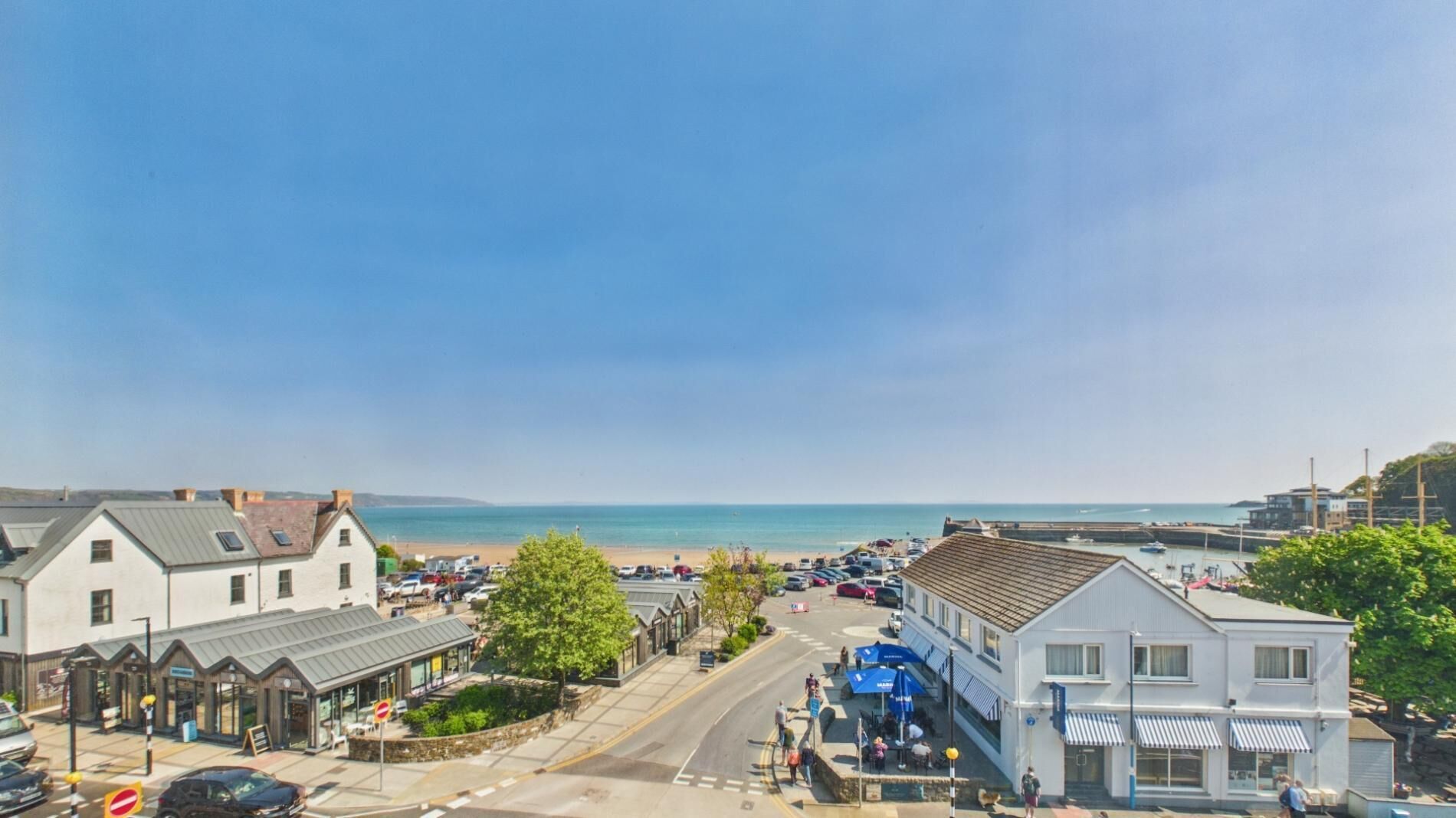 A coastal town with buildings, a beach, and a clear sky.
