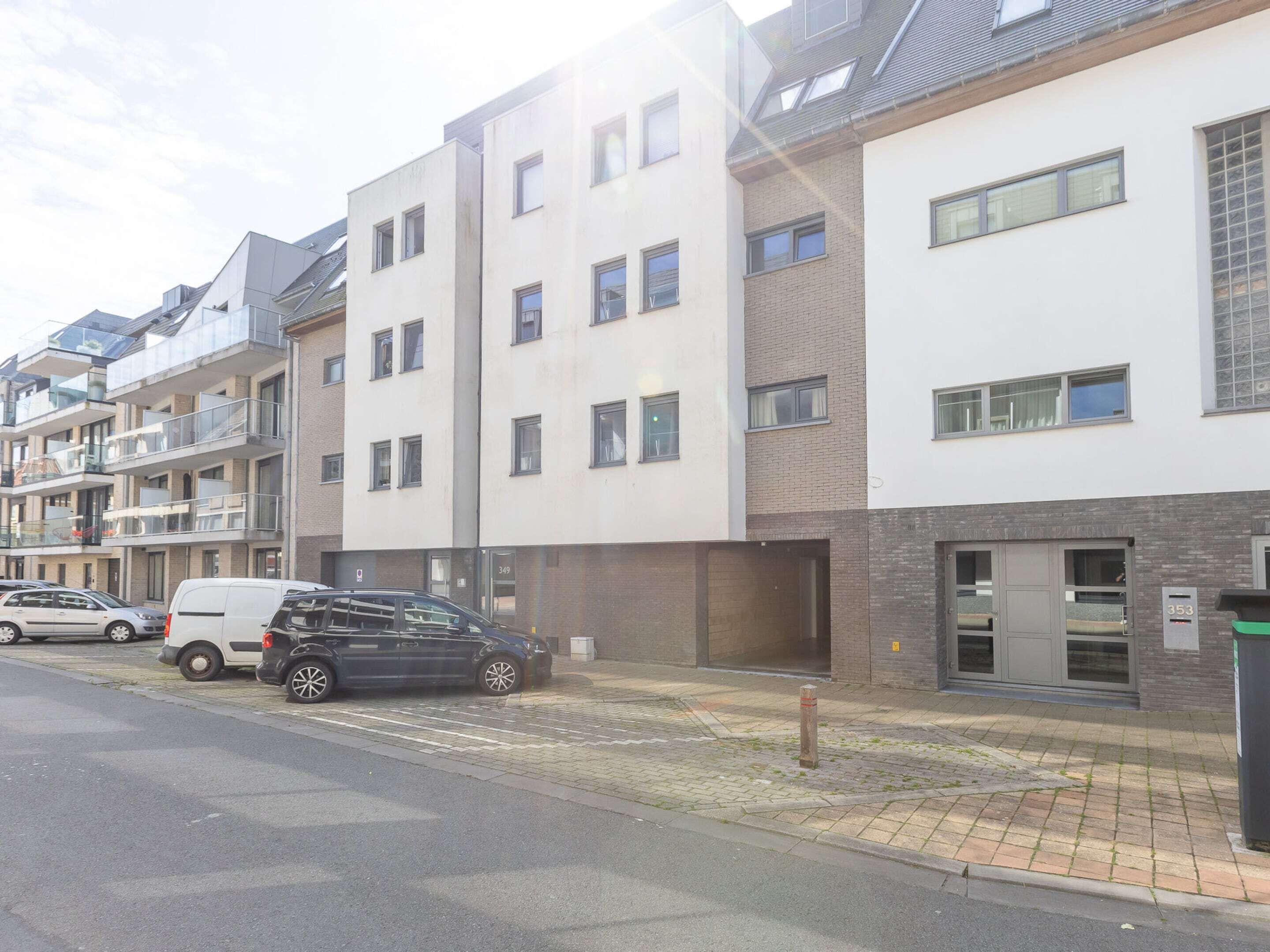 Un immeuble résidentiel à plusieurs étages, doté d’une architecture moderne, avec des balcons et une façade combinant brique et enduit.