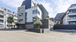 A modern apartment building with a flat roof, large windows, and a brick facade. - Bright Apartment With Sunny Terrace (Middelkerke)