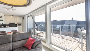 A modern apartment with a kitchen, dining area, and a balcony with a view of the city. - Bright Apartment With Sunny Terrace (Middelkerke)