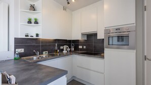 A modern kitchen with white cabinets, a black backsplash, and stainless steel appliances. - Bright Apartment With Sunny Terrace (Middelkerke)