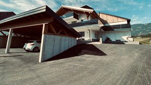 Una moderna casa a due piani con un vialetto coperto e un'auto parcheggiata all'interno.