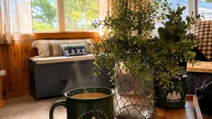 A cozy room with a wooden bench, a potted plant, and a tray with a mug and candle.