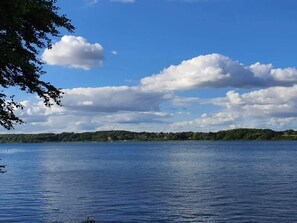 A calm lake with a clear sky and scattered clouds.