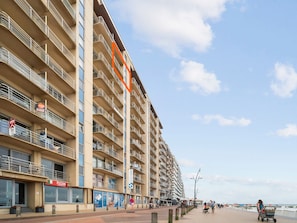 A multi-story hotel with balconies, a visible restaurant on the ground floor, and a clear sky.