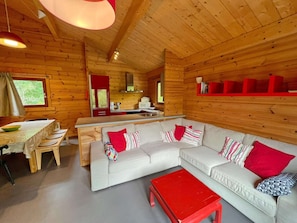 Un acogedor interior de cabaña con comedor, cocina y un sofá con almohadones.