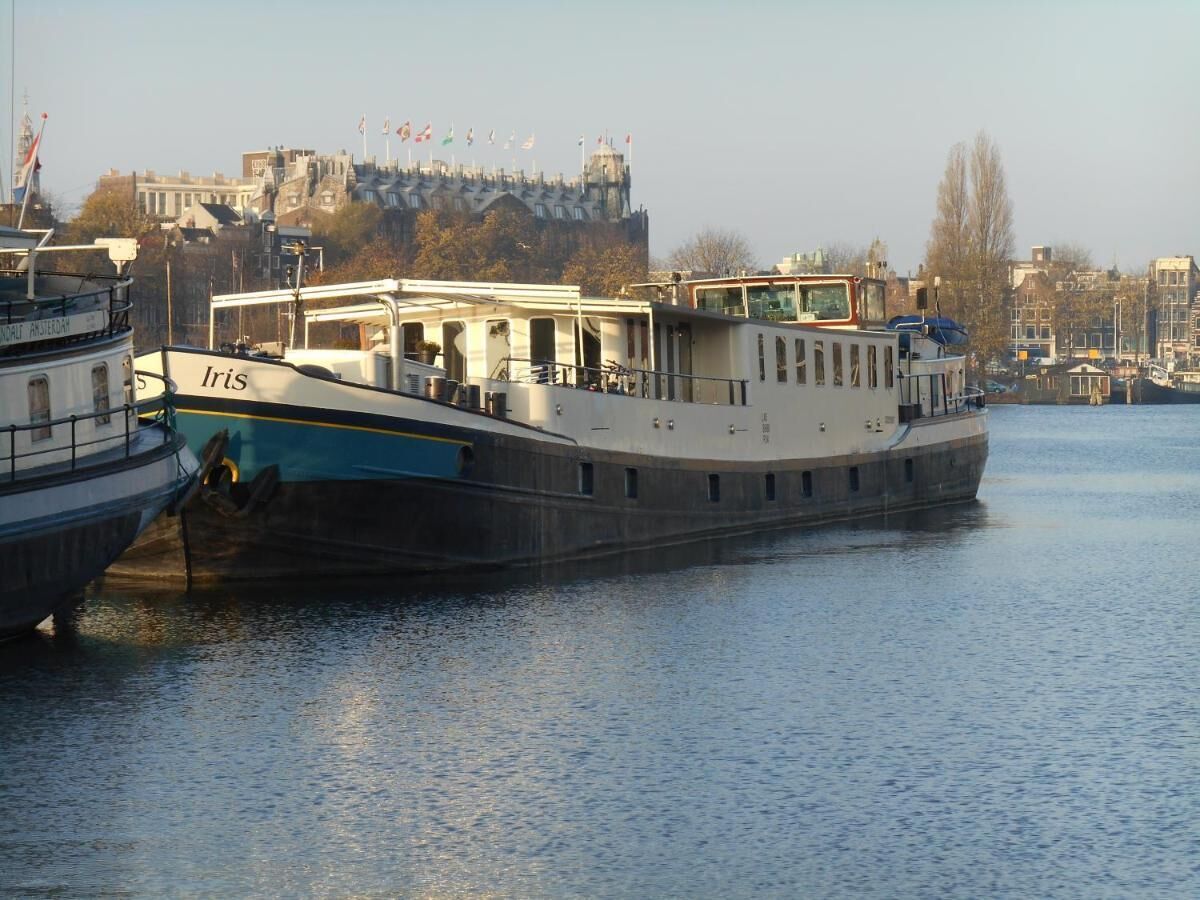 A riverboat docked at a pier with a view of a castle-like building in the background.
