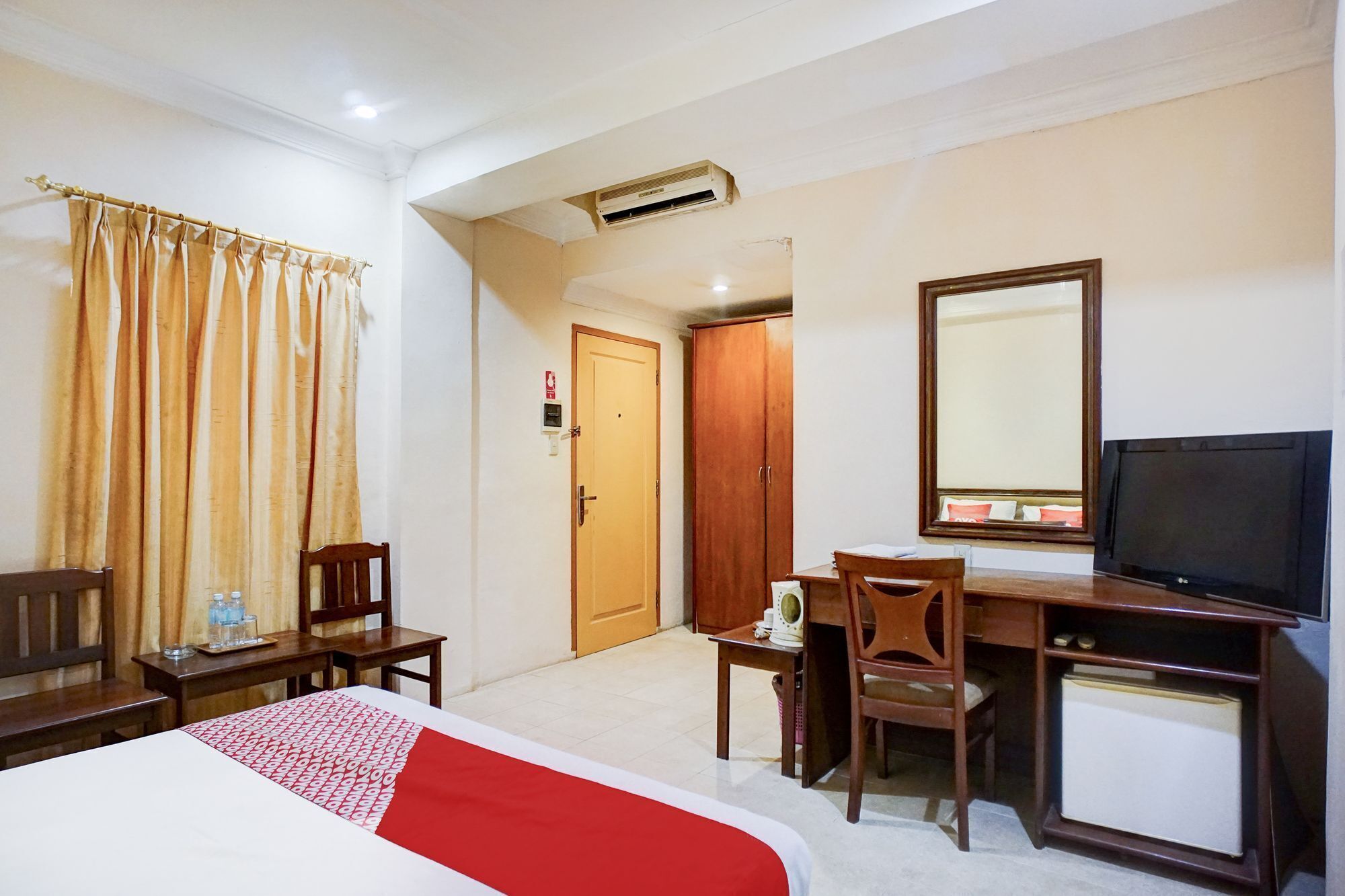 A hotel room with a bed, a desk, a chair, a television, and a wardrobe.