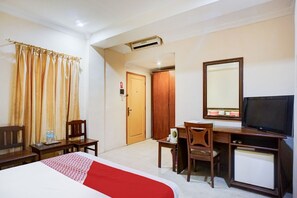 Une chambre d’hôtel comprenant un lit, un bureau, une chaise, une télévision et une armoire.
