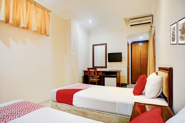 A hotel room with a bed, a desk, a chair, a television, and a wardrobe. - Collection O Peunayong Near Masjid Raya Baiturrahman Formerly Siwah Hotel (Banda Aceh)