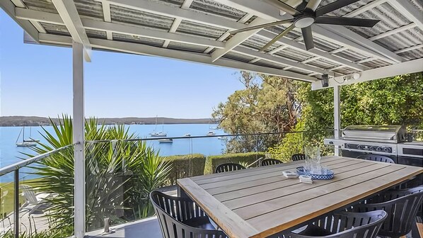 Un espacio de comedor al aire libre techado con vista al mar y barcos.