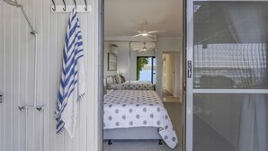 Un dormitorio con cama, ventilador de techo, ventana y puerta.