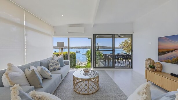 Una sala de estar moderna con sofá, mesa de centro y vistas al mar a través de amplios ventanales.