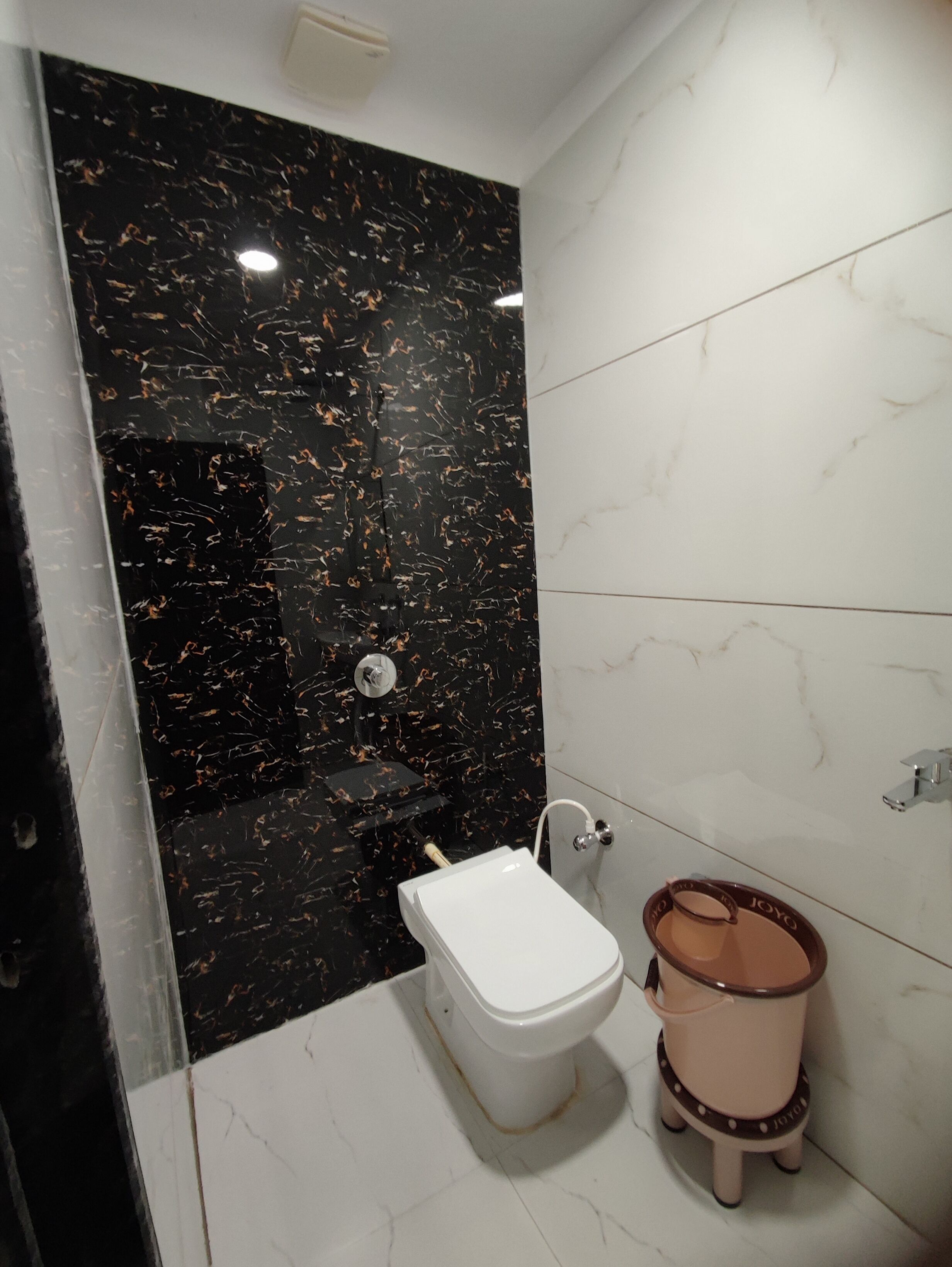 Een badkamer met een toilet, een bidet en een wand van zwart marmer.