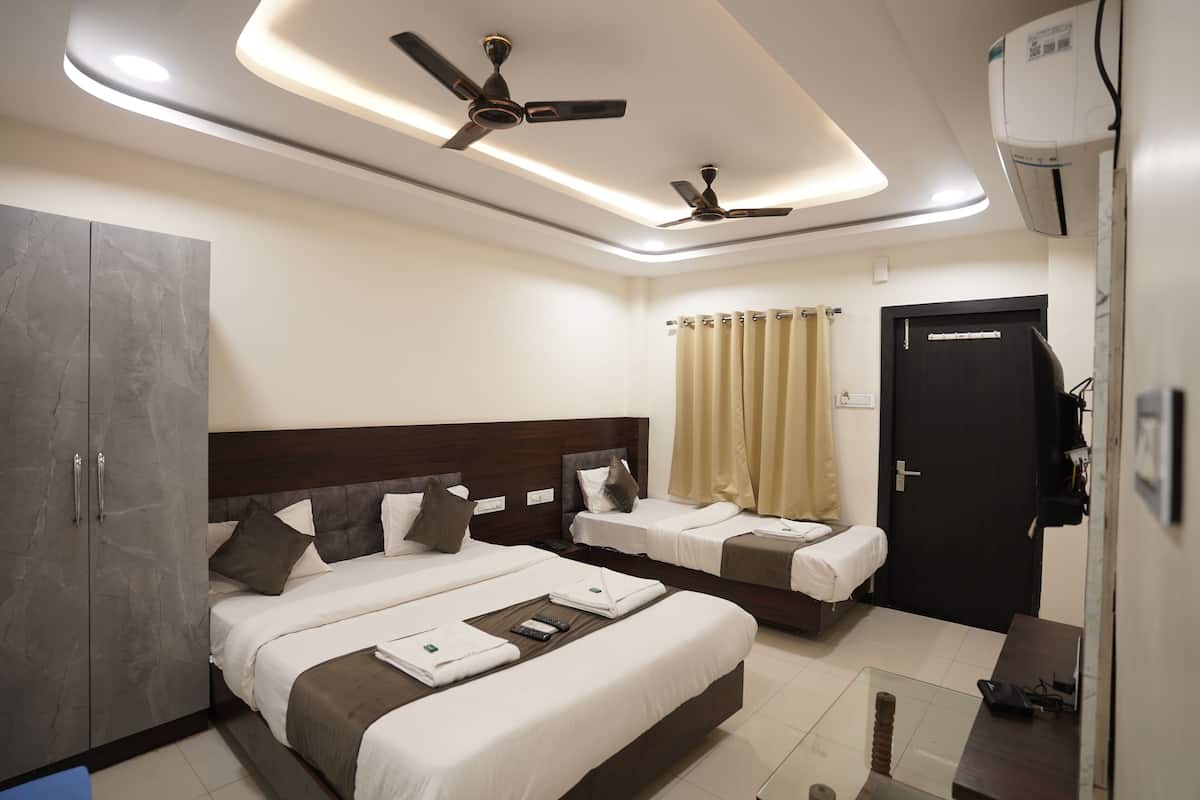 A hotel room with two beds, a wardrobe, a desk, and ceiling fans.