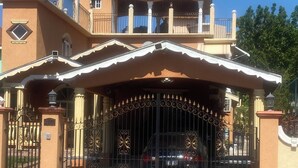 Une maison à deux étages, dotée d’une entrée fermée par un portail, d’un balcon et d’un toit rouge.