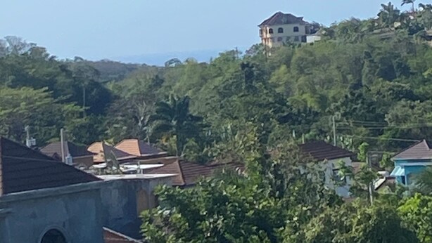 Un quartier résidentiel avec des maisons construites sur une colline, entouré de verdure.