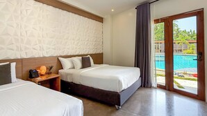 Ein Hotelzimmer mit zwei Betten, einem Holzkopfstück, einer strukturierten Wand, einem Nachttisch mit Lampe und Blick auf einen Außenpool.