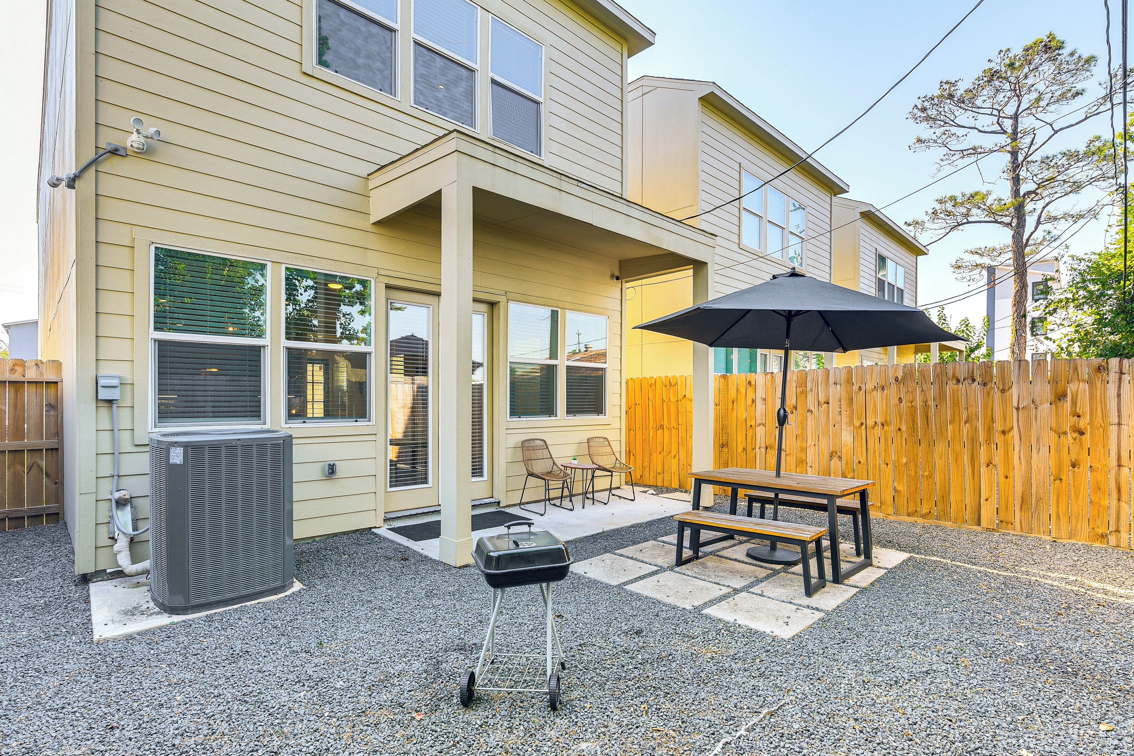A house with a patio area, a grill, and a table with chairs.