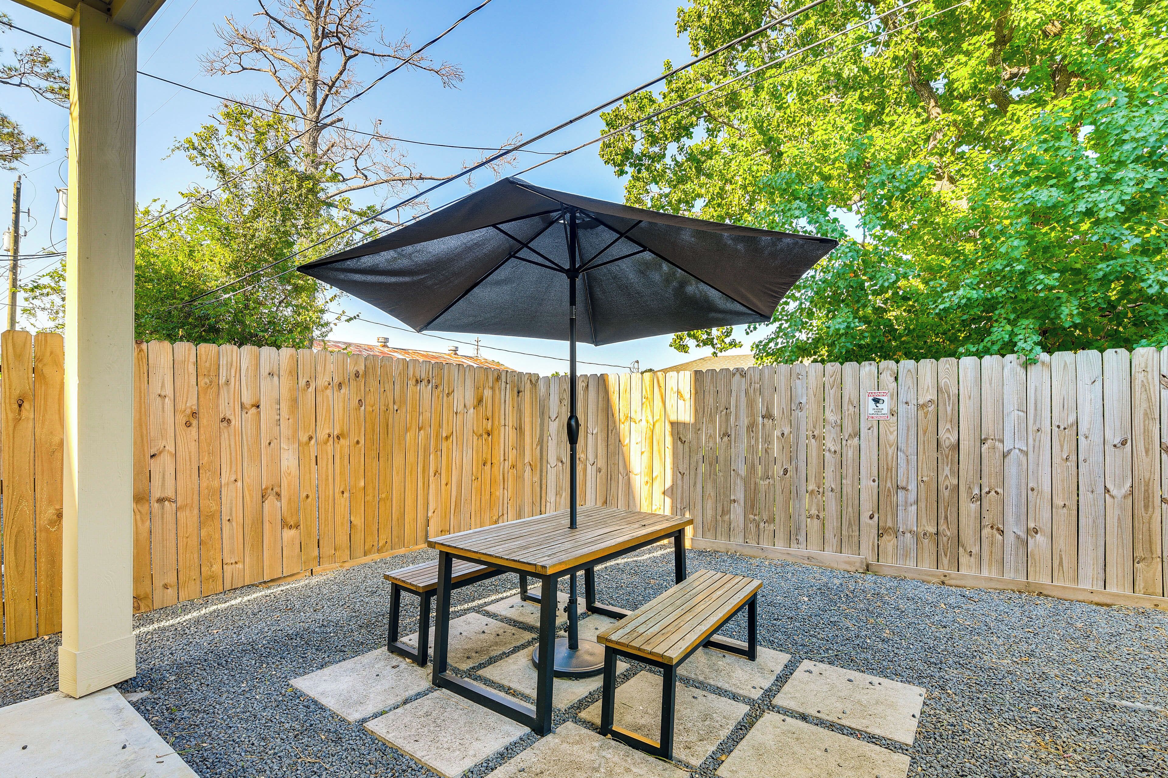 Une terrasse avec une table et des bancs, entourée d’une clôture en bois et recouverte de gravier.