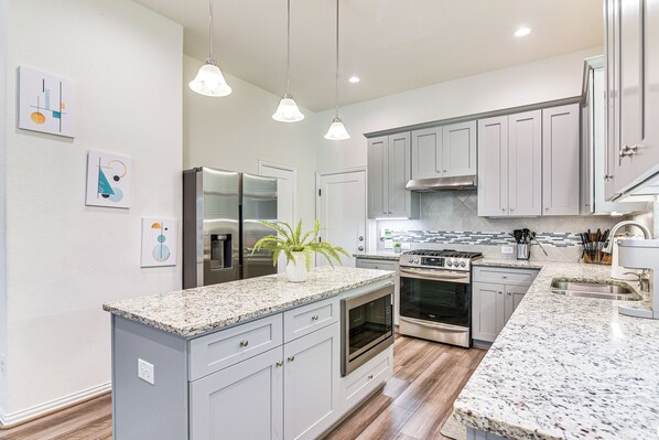 A modern kitchen with granite countertops, stainless steel appliances, and light gray cabinetry. - 5 Mi to Downtown - Chic Home w/ Patio in Houston! (Houston)