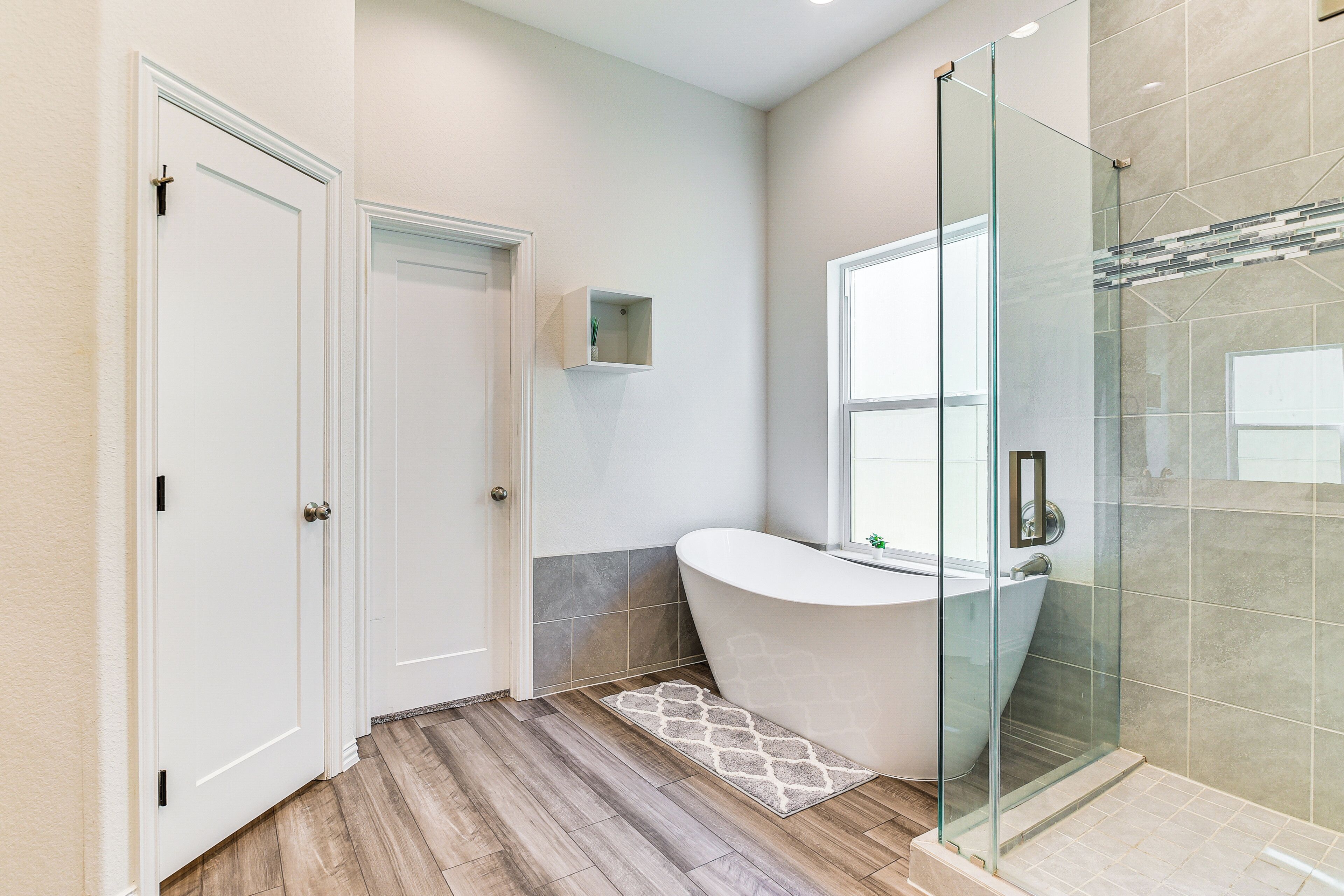 Une salle de bain moderne avec une baignoire sur pieds, une douche à parois de verre et un plancher en bois.