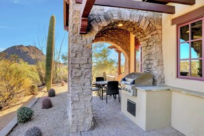 An outdoor patio with a stone archway, a grill, and a table with chairs. - The Rocks Residence Club | Private Plunge Pool, Troon Golf, Clubhouse (Scottsdale)