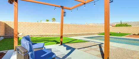 An outdoor patio with wicker furniture and a pergola structure.