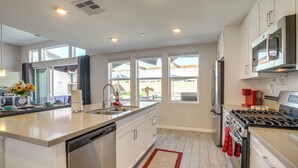 Una cocina moderna con lavavajillas, estufa, refrigerador y ventanas amplias.
