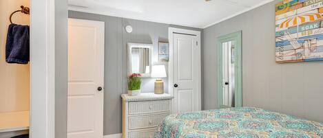 A bedroom with a bed, dresser, and a ceiling fan.