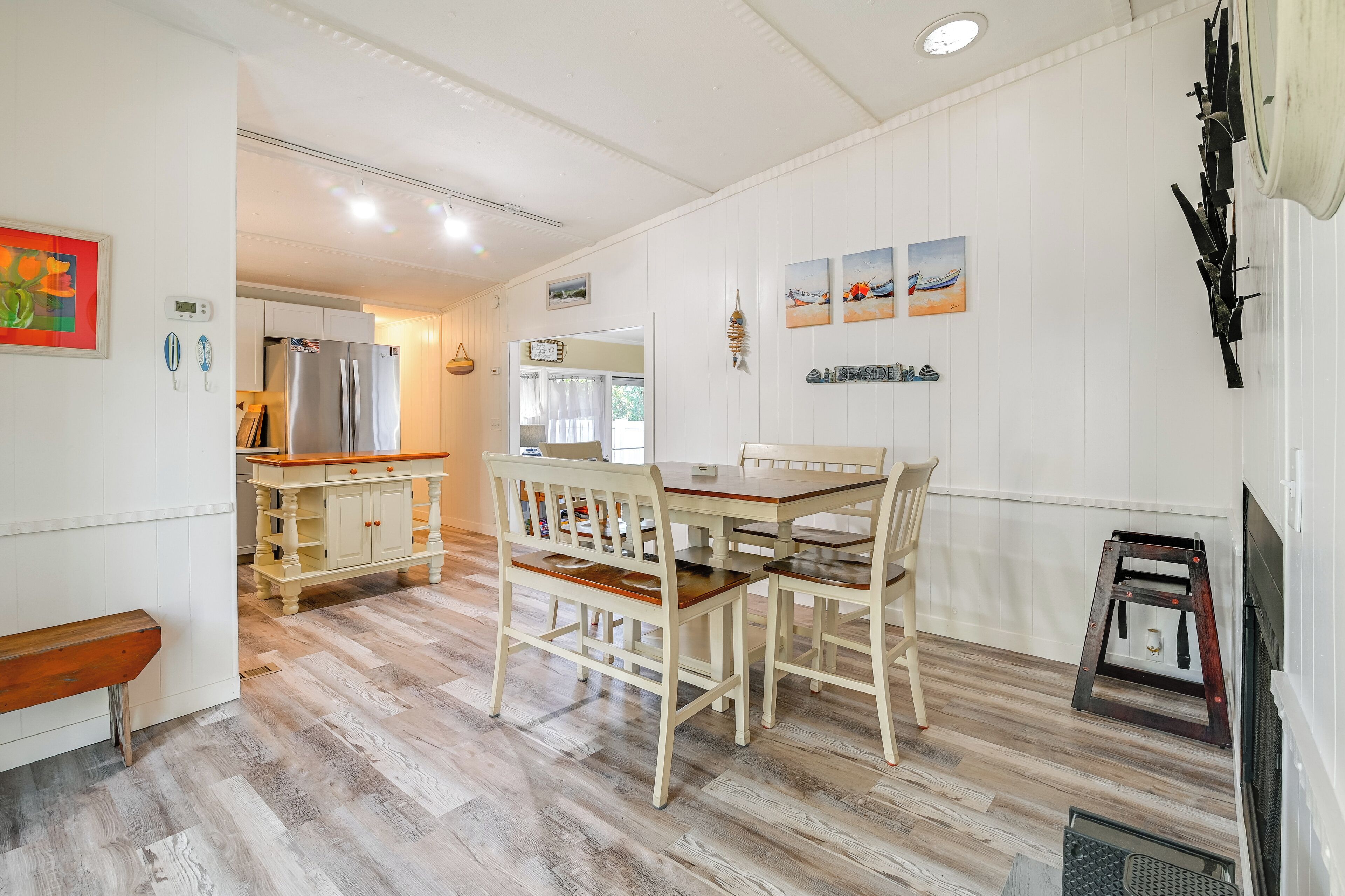 A modern kitchen with a dining area, wooden flooring, and a built-in refrigerator.