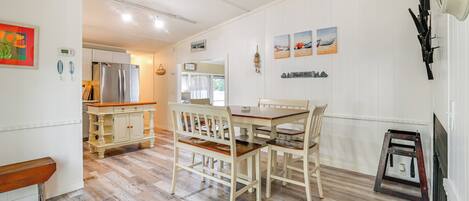 A modern kitchen with a dining area, wooden flooring, and a built-in refrigerator.