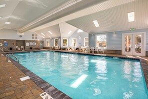 An indoor swimming pool with clear water, surrounded by white chairs and tables, and a brick pathway leading to the pool. - Steps to Ocean: Surfside Beach Home w/ Patio (Murrells Inlet)